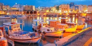 Old harbour of Heraklion with fishing boats and marina during twilight blue hour, Crete, Greece. Boats blurred motion on the foreground.